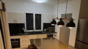 Eine moderne Küche mit Kochinsel, Barhocker und Pendelleuchten.