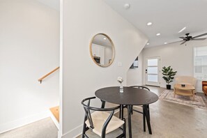 A modern living room with a round dining table, two chairs, a round mirror, a ceiling fan, and a potted plant. - NEW-Swamp House-Luxury Amenities-65` TV-Fast WiFi (Lafayette)