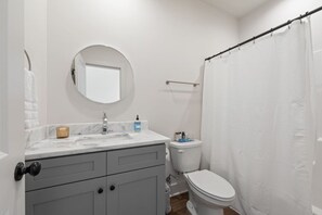 A bathroom with a white sink, mirror, and toilet. - NEW-Swamp House-Luxury Amenities-65` TV-Fast WiFi (Lafayette)