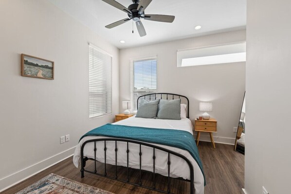 A bedroom with a bed, bedside tables, a ceiling fan, and a window with blinds.