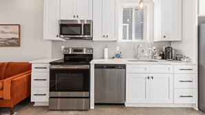 Una cocina moderna con gabinetes blancos, electrodomésticos de acero inoxidable y un horno empotrado.