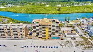 Ein Hotel an der Küste mit mehreren Gebäuden, einem Schwimmbad und einem Strandbereich mit Liegestühlen.