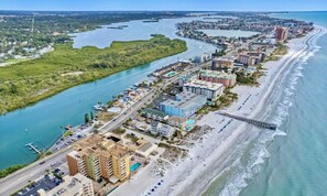 Vista aérea de una ciudad costera con un puerto deportivo, hoteles frente a la playa y un puente que conecta la parte continental con una isla.