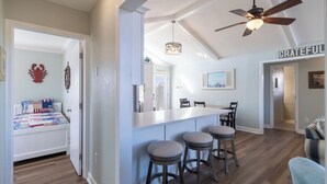 A modern kitchen with a bar area, a ceiling fan, and a 'GRATEFUL' sign on the wall. - Ocean Views, Gorgeous! Dogs Welcome, Hot Tub, SN9805 (Nags Head)