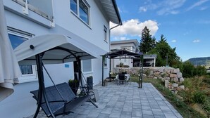 A patio area with a swing chair, a table, and a covered seating area. - Holiday Apartment Moises y Ruth with beautiful garden (Murg)