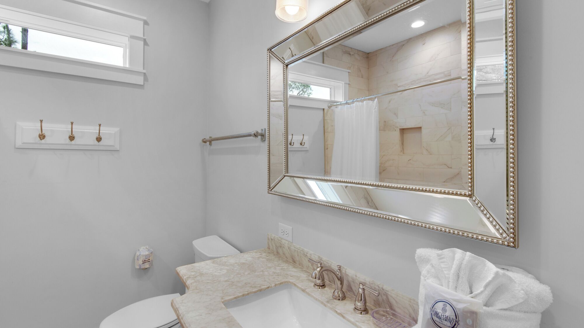 A bathroom with a large mirror, a sink, and a toilet.