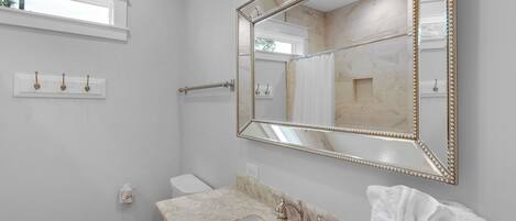 A bathroom with a large mirror, a sink, and a toilet.