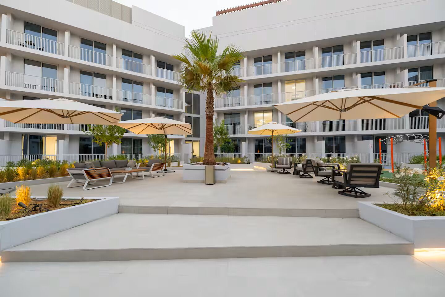 Ein mehrstöckiges Hotel mit Außenbereichen, Palmen und modernem Design.
