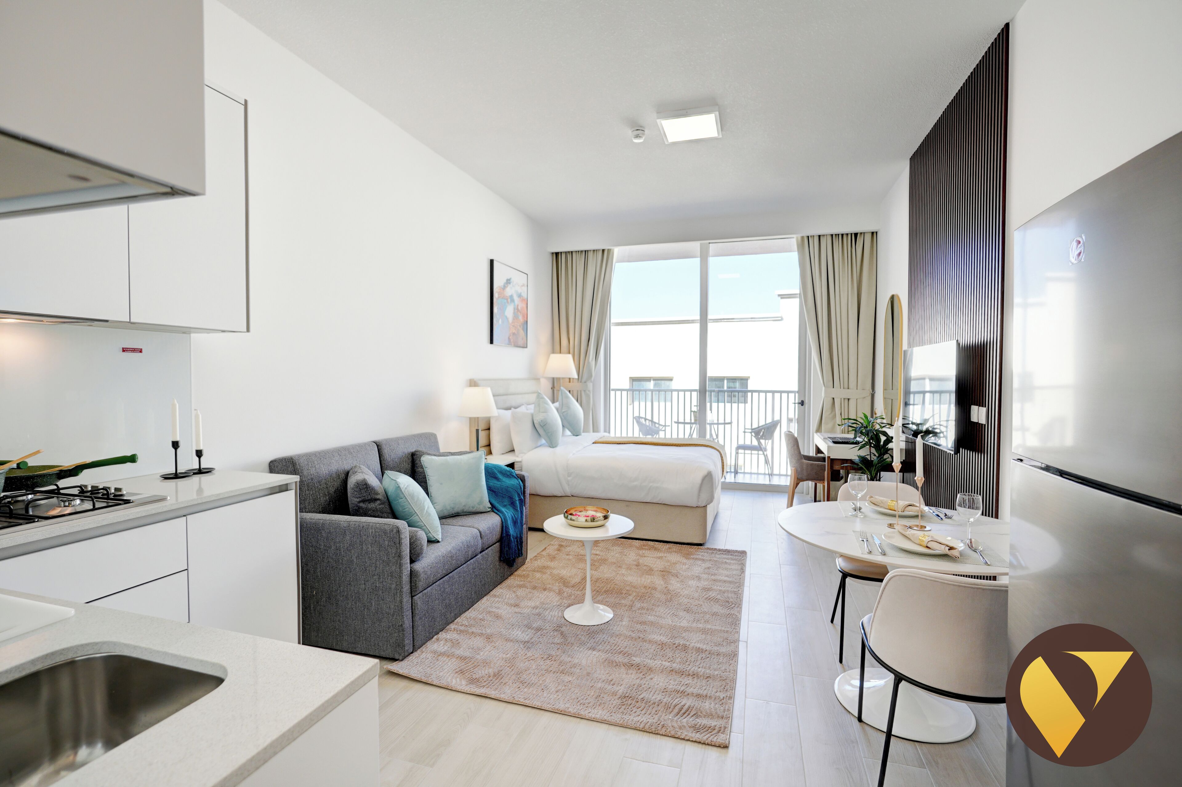 Et moderne hotelværelse med tekøkken, spiseplads, seng og balkon med udsigt.