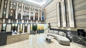 Eine moderne Lobby mit einer Rezeption, einer Sitzecke und einer großen Wand mit vertikalen Paneelen.