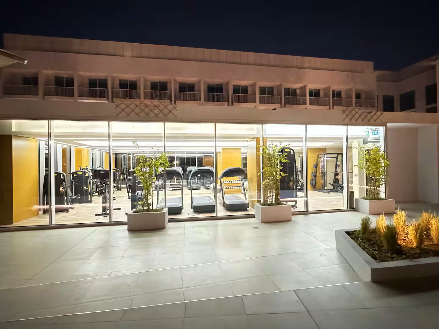 A modern building with a glass entrance leading to a gym area.