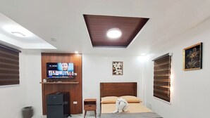A bedroom with a bed, a TV, a small desk, and a refrigerator. - Perfect getaway beach resort with a great view of Subic bay  (Olongapo)