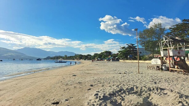 A beach with a lifeguard station, clear skies, and boats in the water. - Perfect getaway beach resort with a great view of Subic bay  (Olongapo)