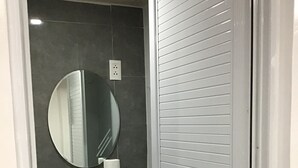 A bathroom with a white sink, a round mirror, and a toilet. - Perfect getaway beach resort with a great view of Subic bay  (Olongapo)