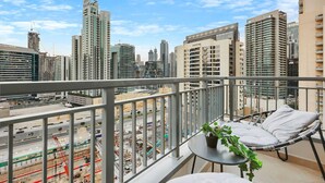A balcony with a view of a cityscape, including high-rise buildings and construction sites. - Walk to Dubai Mall | 2BR Apartment with Balcony and Pool (Downtown)