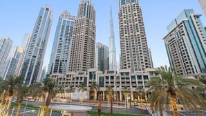 A high-rise building complex with multiple skyscrapers, including a prominent tower with a spire. - Walk to Dubai Mall | 2BR Apartment with Balcony and Pool (Downtown)