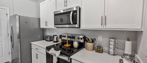 Una cocina moderna con armarios blancos, electrodomésticos de acero inoxidable y un microondas.