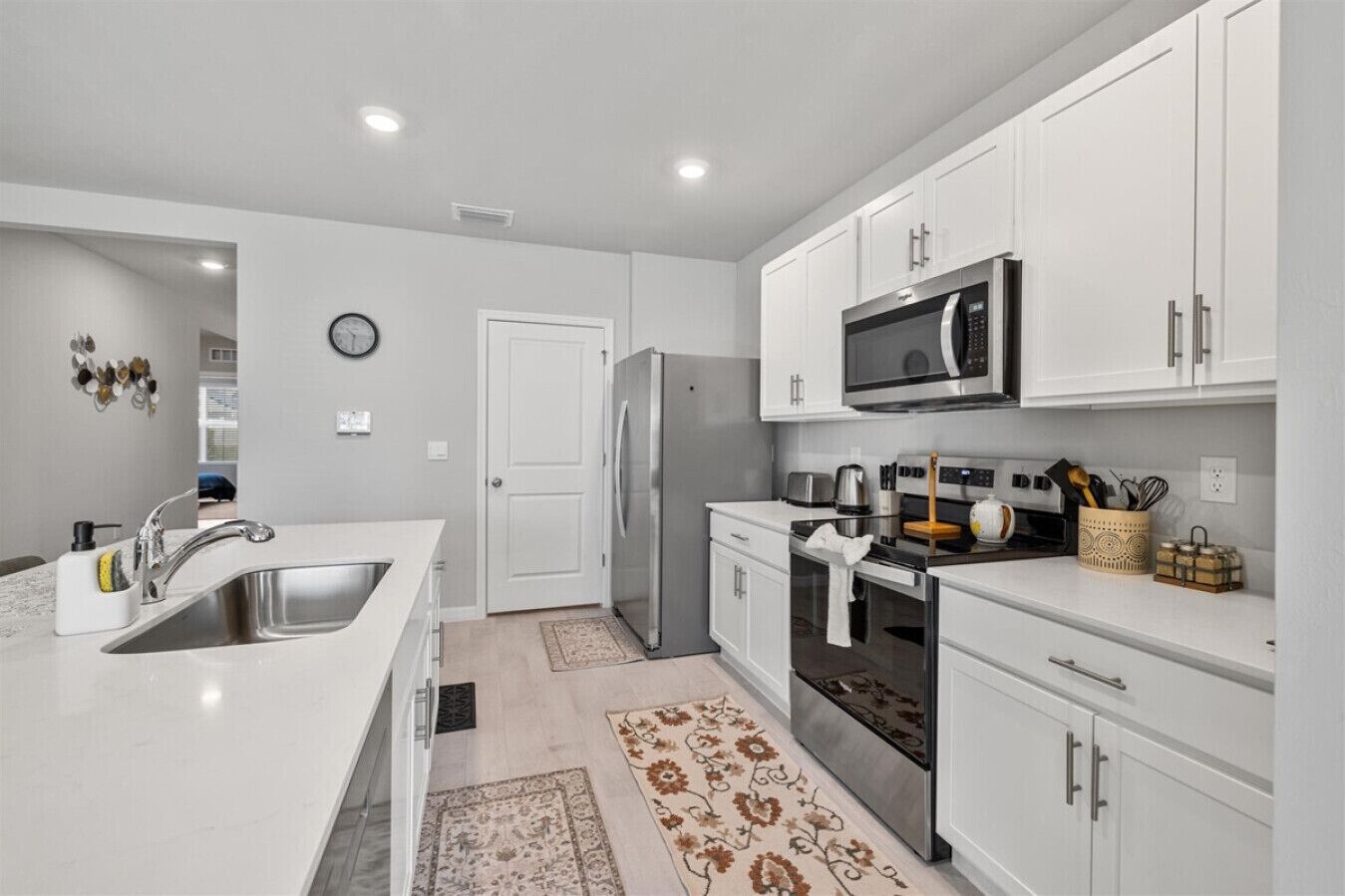 A modern kitchen with white cabinetry, stainless steel appliances, and a central island with a sink.