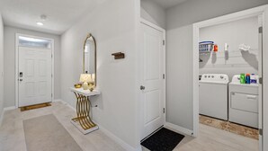 A clean, modern bathroom with a vanity, a mirror, a washing machine, and a laundry basket.