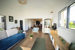 Un salon moderne avec un canapé, une table à manger et un coin cuisine à l’arrière-plan.