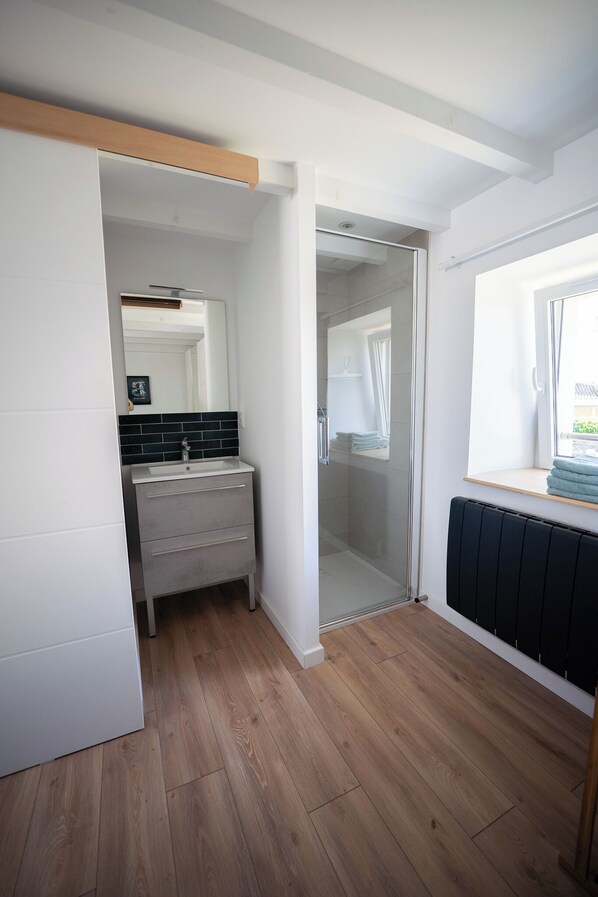 Een moderne badkamer met een douche, wastafel en een raam.