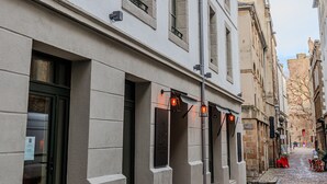 A building with multiple windows and doors, a cobblestone street, and a clear sky. - Appartements d'Anne - Saint Malo (Saint-Malo)