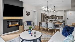 Een moderne woonkamer met een open haard, eethoek en keuken.