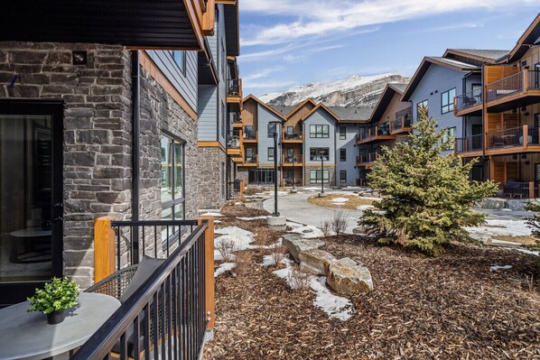 A modern building with stone and wood exterior, multiple balconies, and a snow-covered landscape.