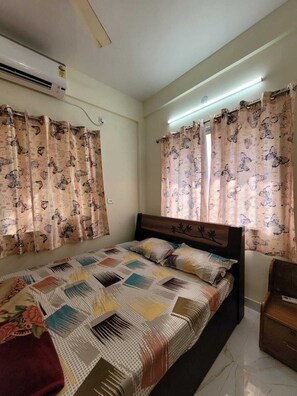 Relax in a stylish bedroom with a large bed, wooden headboard, and air conditioning for a comfortable stay.