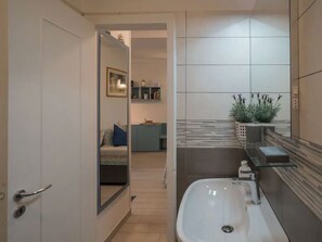 A modern bathroom with a white sink, a mirror, and a potted plant. - CORNABRUGIA: Modern Open Space with Private Patio - AC & 2' to Beach (Vernazza)