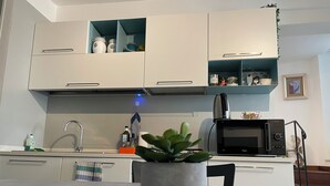 A modern kitchen with white cabinets, a microwave, and a sink. - CORNABRUGIA: Modern Open Space with Private Patio - AC & 2' to Beach (Vernazza)