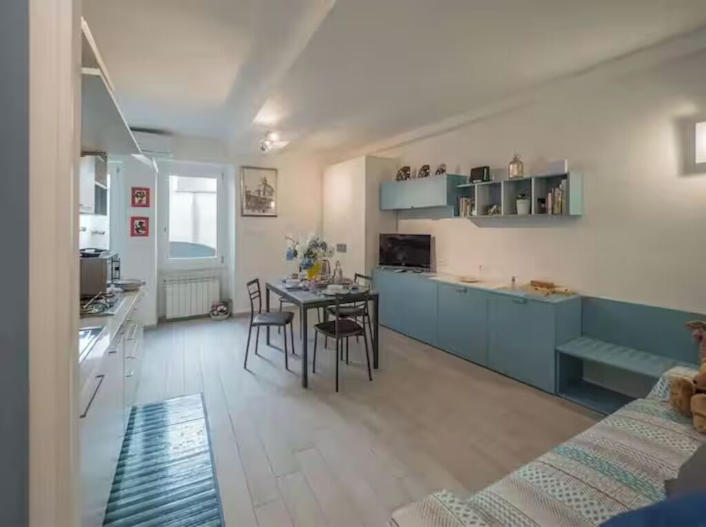 Ett kompakt bostadsutrymme med ett litet kök, en matplats och en soffa.