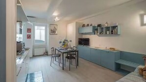 A compact living space with a kitchenette, dining area, and a sofa. - CORNABRUGIA: Modern Open Space with Private Patio - AC & 2' to Beach (Vernazza)