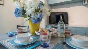 A dining table set with plates, bowls, and a vase of flowers. - CORNABRUGIA: Modern Open Space with Private Patio - AC & 2' to Beach (Vernazza)