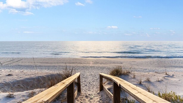 A wooden boardwalk leading to a beach with a clear sky. - Pool | Gulf Views | Outdoor Shower (Port St. Joe)