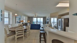 Una cocina moderna con comedor, ventanas amplias y vista al océano.