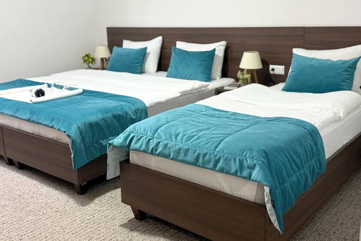 Two twin beds with teal bedding, wooden headboards, and bedside lamps.