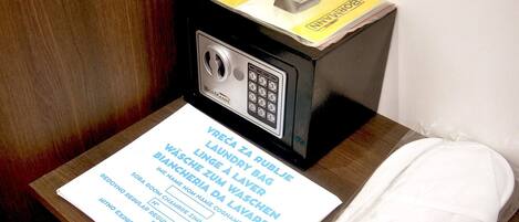 A room with a black minibar, a white towel, and a paper with text in a foreign language.