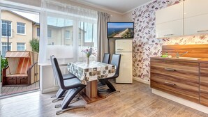 Eine moderne Küche mit Holzschränken, einem Esstisch mit Stühlen und einem Fernseher an der Wand.