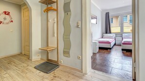 Ein modernes Hotelzimmer mit Holzboden, einem Platz für Haustiere, einem Spiegel, einem Holzbodenregal und einem Bett mit weißer Bettwäsche.