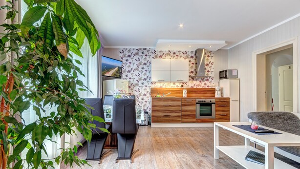 Ein modernes Wohnzimmer mit Essbereich, einer Küche mit Holzschränken und einem großen Fenster mit Blick.