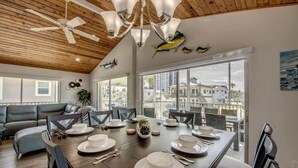 Comedor con techo de madera, ventanas amplias y vista a edificios.