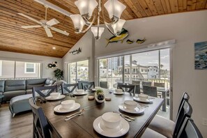 A dining area with a wooden ceiling, large windows, and a view of buildings outside.