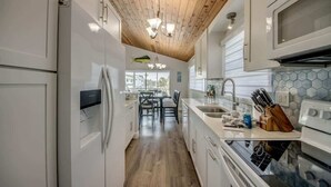 Una cocina moderna con armarios blancos, techo de madera y vistas al exterior.
