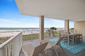 Un balcone con vista sulla spiaggia, un tavolo e sedie.