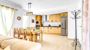 Una cucina moderna con mobili in legno, un frigorifero in acciaio inossidabile e un'area pranzo con sedie e tavolo in legno.