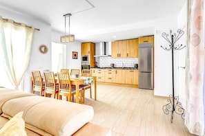 A modern kitchen with wooden cabinets, a stainless steel refrigerator, and a dining area with wooden chairs and a table. - Villa 'Chispita For Groups' with Mountain View, Wi-Fi and Air Conditioning (Fuengirola)