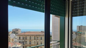 A balcony with a view of the sea and buildings.