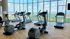 Ein Fitnessraum mit Cardiogeräten und Blick auf eine Stadtlandschaft durch große Fenster.