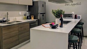 Eine moderne Küche mit Kochinsel, Edelstahlgeräten und einer Bar mit Hockern.